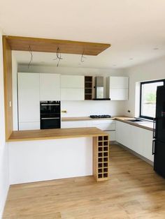 an empty kitchen with wooden floors and white cabinets, black appliances and wood flooring