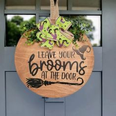 a wooden sign that says leave your brooms at the door hanging on a front door