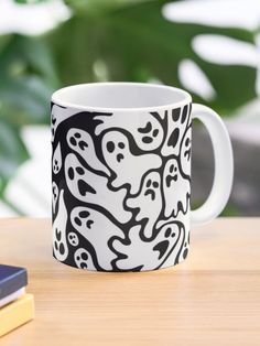 a black and white coffee mug sitting on top of a table next to a book