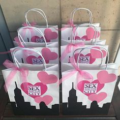 six bags with pink hearts tied to them sitting on a shelf in front of a building