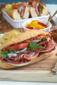 a sandwich with meat and vegetables on a cutting board