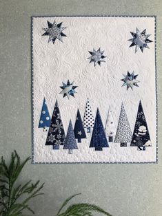 a quilted wall hanging with christmas trees and stars