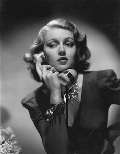 an old black and white photo of a woman talking on the phone with her hand near her face