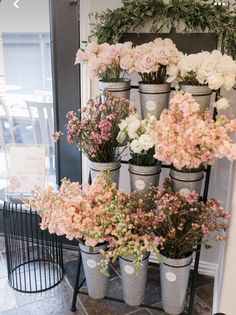 a bunch of potted flowers sitting on top of a metal stand in front of a door