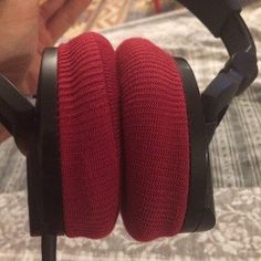 a pair of red headphones sitting on top of a bed next to a person