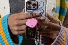 a person holding a cell phone with a pink case on it and a keychain