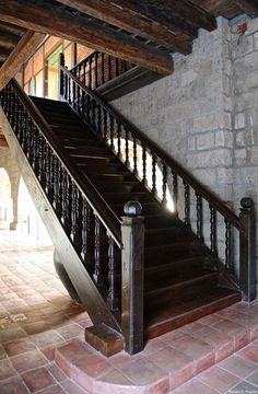 the stairs are made of wood and wrought iron, with brick flooring on both sides