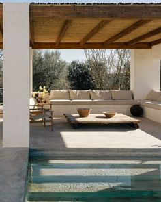 an outdoor living area with couches and tables next to a pool in the sun