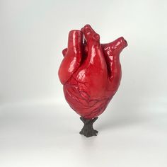 a red heart shaped sculpture sitting on top of a tree stump in front of a white background