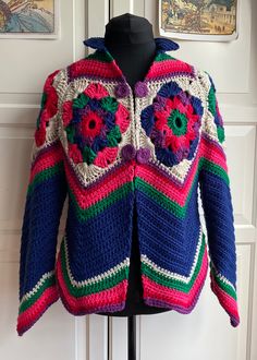 a colorful crocheted jacket is hanging on a mannequin's dummy