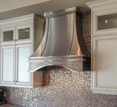 a stove top oven sitting inside of a kitchen next to white cupboards and drawers