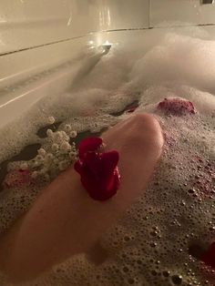 a bathtub filled with lots of foam and red hearts floating in it's water