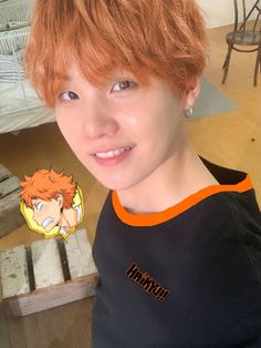 a young man with red hair is smiling at the camera while wearing an orange and black t - shirt