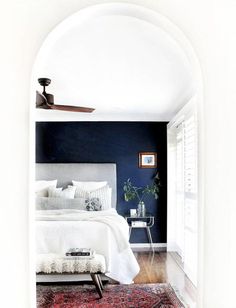 a bedroom with blue walls, white bedding and a red rug on the floor