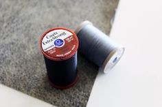 two spools of thread sitting next to each other on the floor in front of a white wall