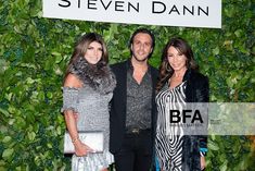 two women and a man standing next to each other in front of a green wall