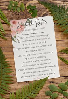 the wedding stationery is surrounded by fern leaves and pink flowers on a wooden table