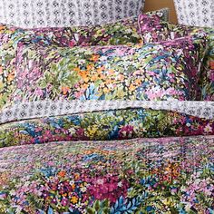 an image of a bed with colorful floral comforter and pillowcases on it