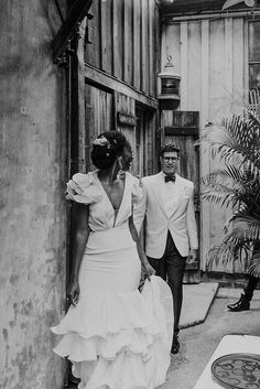 black and white photograph of two people dressed in formal wear walking out of a building