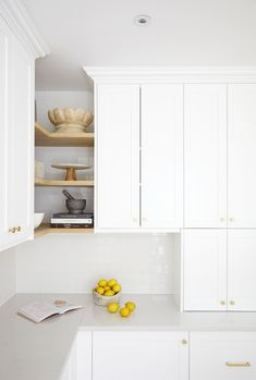 a kitchen with white cabinets and yellow fruit on the counter top in front of it