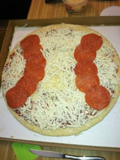 a pizza with pepperoni and cheese on it sitting in a box next to a knife and fork