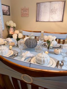 a dining room table set with white dishes and place settings for two people to eat