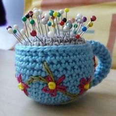 a crocheted cup with some pins in it