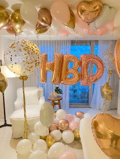 a room filled with balloons that spell out the word h b p in gold, white and pink