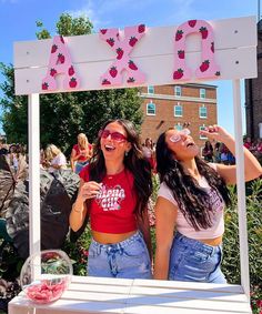 two women standing under a sign that says xxxo