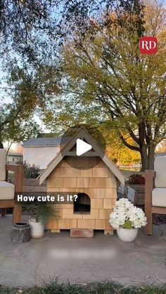 a dog house sitting in the middle of a yard next to some chairs and trees