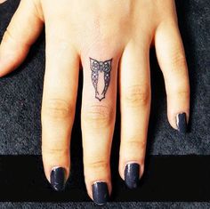 a woman's hand with a small tattoo on the middle finger and an arrow in the middle