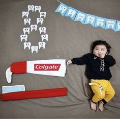 a young child laying on top of a bed next to toothbrushes and dental floss