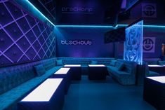 an empty room with blue couches and purple lighting on the walls is lit up by neon lights