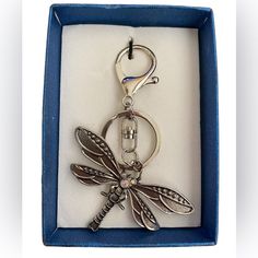 a keychain with a dragonfly on it in a blue box that is open