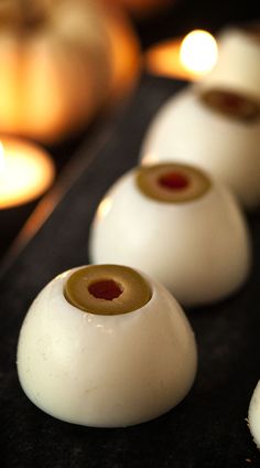 some white candles are lined up on a black surface with one candle in the background