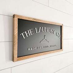 the laundry co wash dry fold sign mounted on a white wall with wood trimming