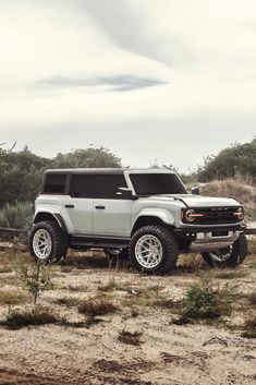 a silver truck parked on top of a dirt field