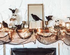 a mantle decorated with halloween decorations, candles and fake birds sitting on top of it