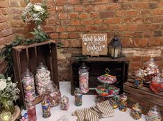 a table topped with lots of candy and candies next to wooden crates filled with flowers