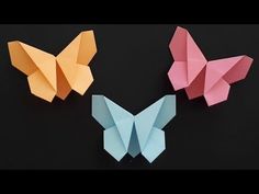 three origami butterflies sitting next to each other on a black surface with one butterfly facing the camera