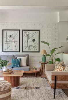 a living room with two couches, coffee table and potted plants on the wall