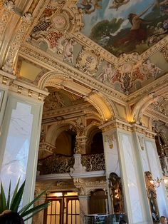 an ornately decorated room with paintings on the walls and ceiling, along with potted plants