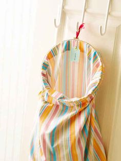 a colorful striped bag hanging on a white coat rack next to a door with a tag