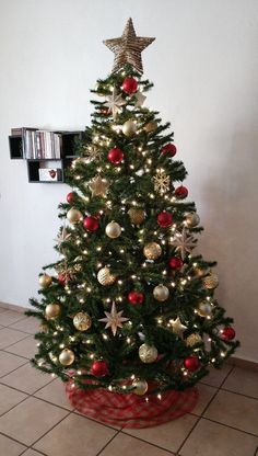 a small christmas tree with red and gold ornaments in a potted planter on the floor