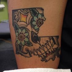 a tattoo on the leg of a woman with flowers and leaves in it's center