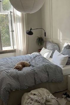 a dog laying on top of a bed in a room with striped sheets and pillows