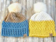 two knitted hats with pom - poms on them