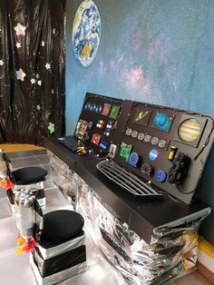 a desk with some chairs around it and space themed decorations on the wall behind it