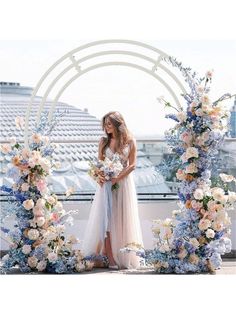 a woman standing in front of an arch with flowers