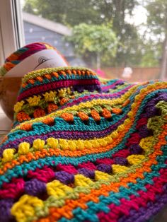 a crocheted blanket sitting on top of a window sill next to a bowl